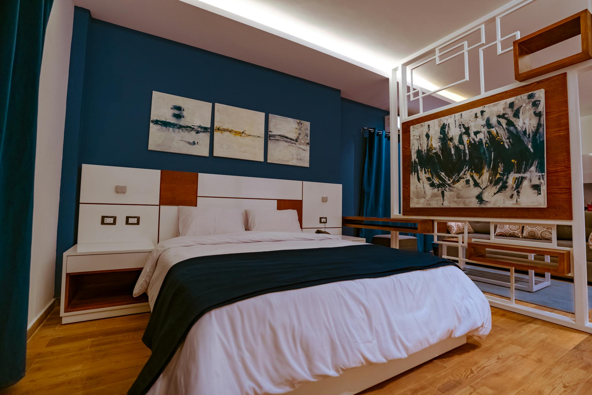 Stylish modern hotel room with abstract paintings and cozy bed, ideal for relaxation.